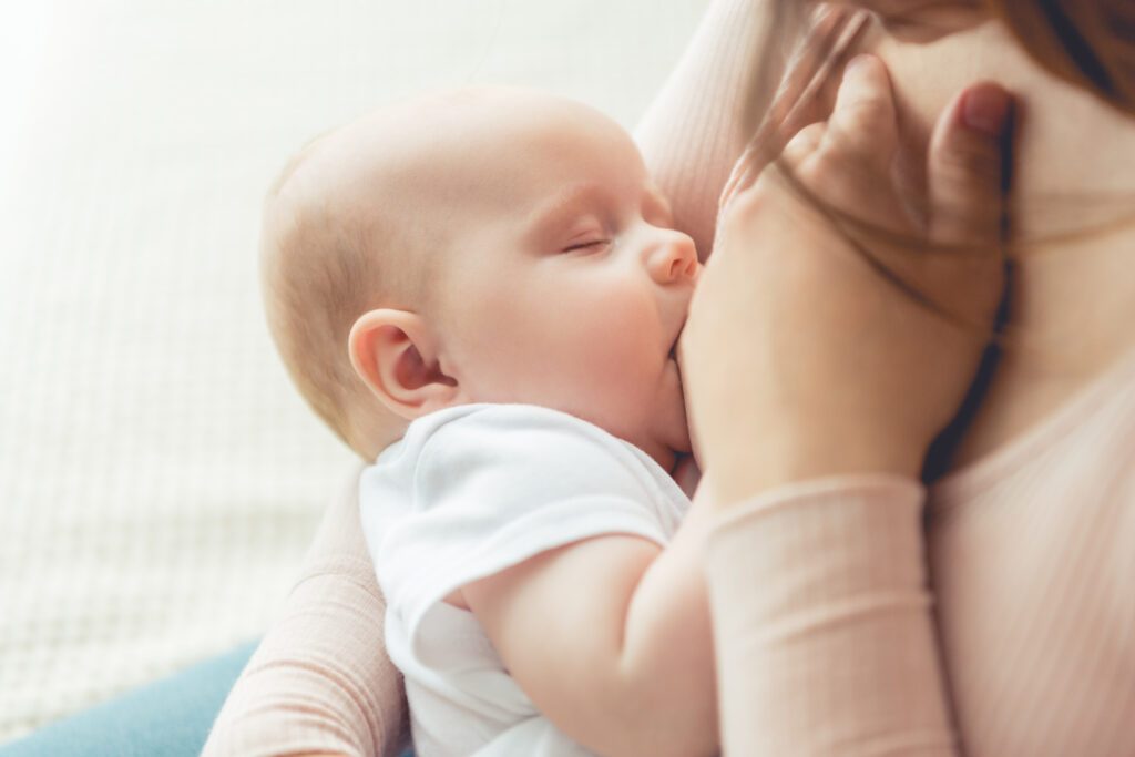 cropped view of mother breastfeeding her child in apartment